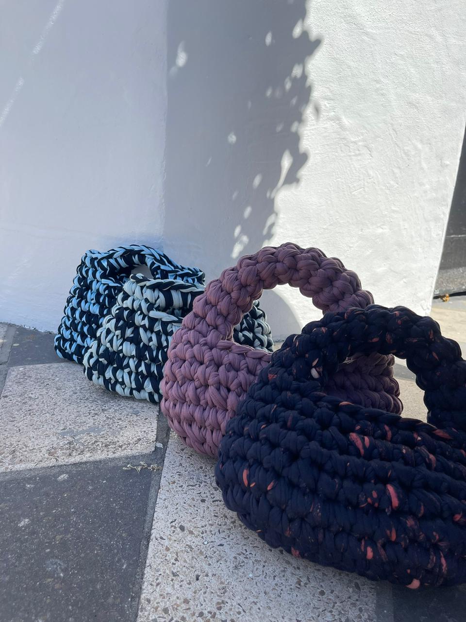 Four crochet handbags arranged in a row